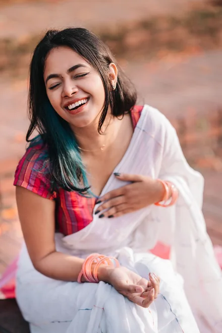 A young woman in a saree, laughing outdoors
